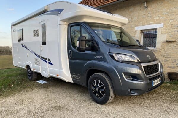 Camping-car moderne Peugeot garé devant une maison