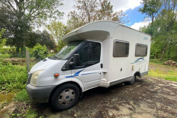 Camping-car blanc stationné en milieu naturel