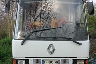 LKW weiß geparkt zwischen Bäumen und Büschen.