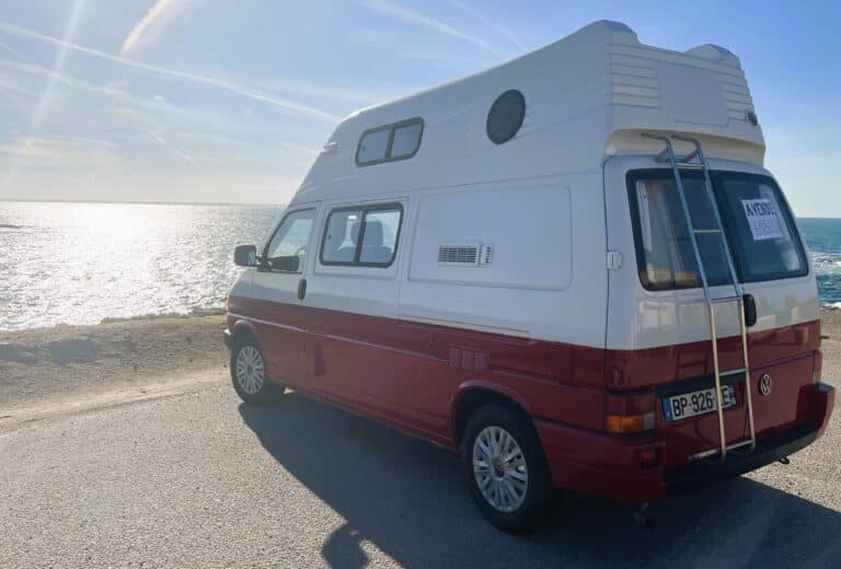 Camping-car Volkswagen rouge et blanc au bord de la mer