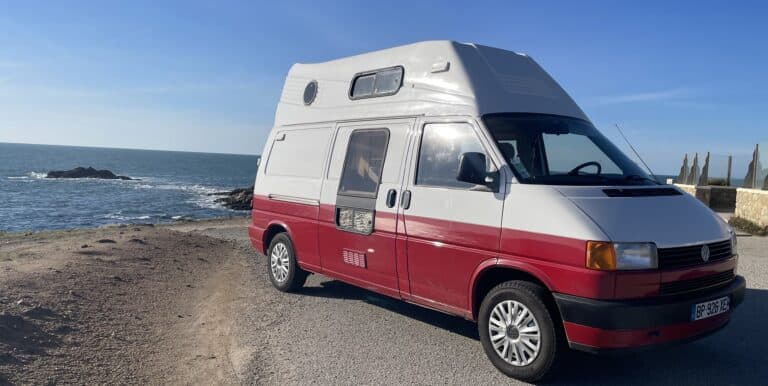 Camping-car rouge et blanc sur un littoral ensoleillé