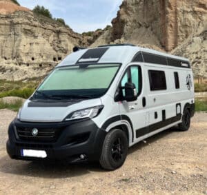 Camping-car moderne devant des formations rocheuses