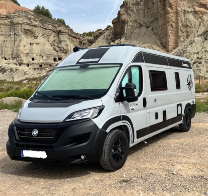 Camping-car moderne devant des formations rocheuses
