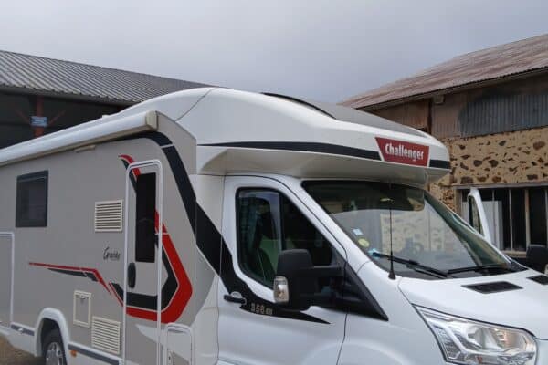 Camping-car blanc Challenger garé devant bâtiment