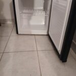 Petit réfrigérateur ouvert sur carrelage beige