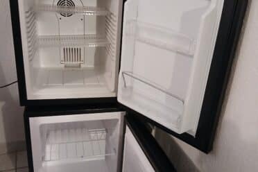 Mini-réfrigérateurs ouverts vides sur sol en carrelage