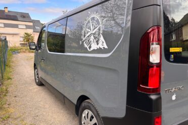 Fourgonnette grise avec logo de montagne sur vitre