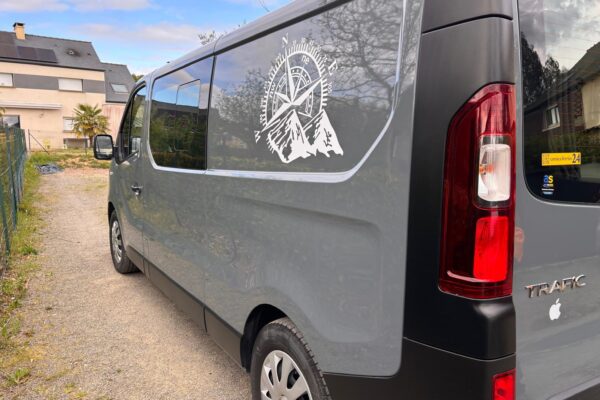 Fourgonnette grise avec logo de montagne sur vitre