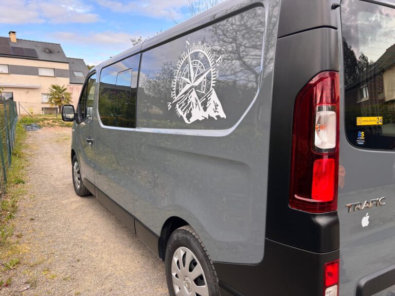 Fourgonnette grise avec logo de montagne sur vitre