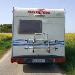 Camping-car stationné près d'un champ de fleurs jaunes