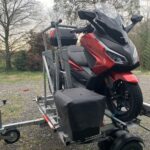Scooter Honda rouge sur remorque en extérieur