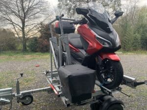 Scooter Honda rouge sur remorque en extérieur