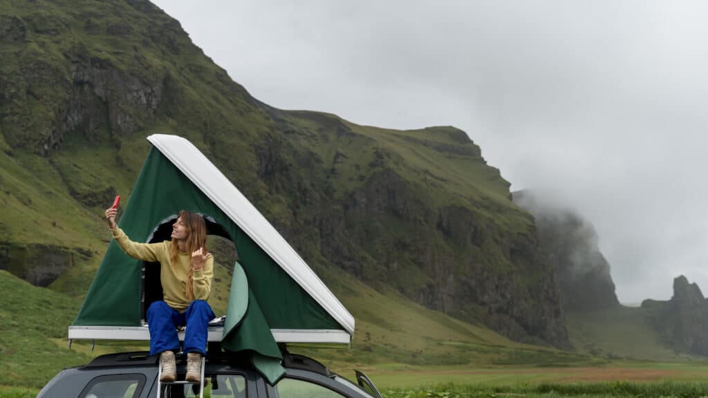 Femme prenant un selfie en montagne depuis un toit de voiture