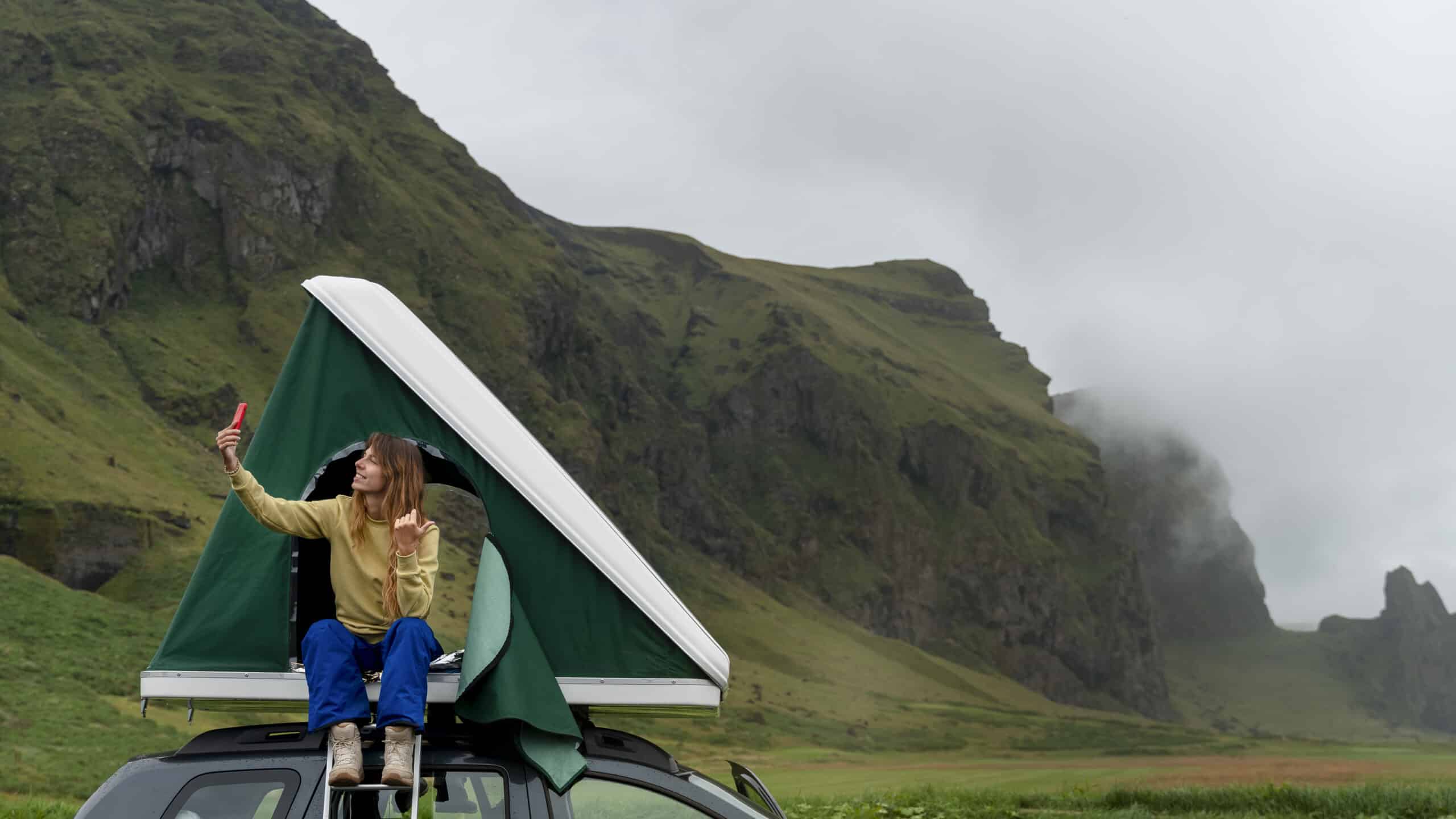 Femme prenant un selfie en montagne depuis un toit de voiture