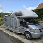 Camping-car gris stationné près d'une route