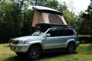 Voiture avec tente sur toit en forêt.
