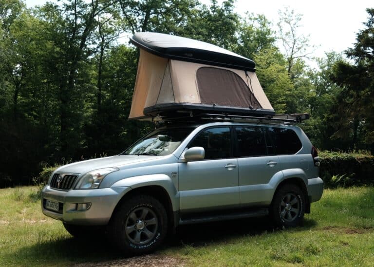 Voiture avec tente sur toit en forêt.