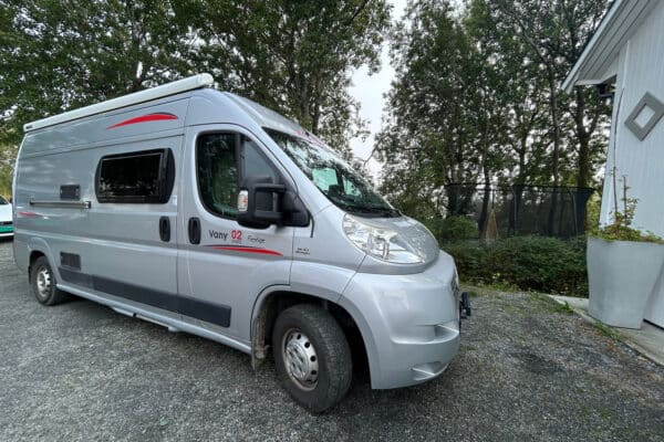 Camping-car gris devant des arbres.