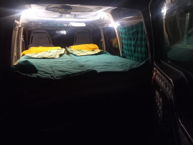 Lit aménagé dans un van avec couverture colorée.