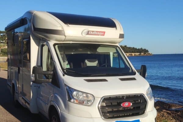Camping-car blanc stationné près de la mer