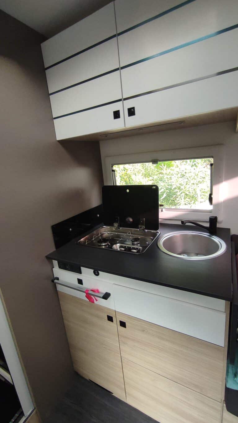 Cuisine compacte de camping-car avec évier et cuisinière.