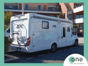 Camping-car stationné devant un immeuble moderne.