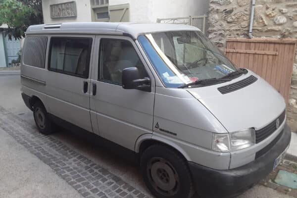 Fourgon gris garé sur une rue pavée.