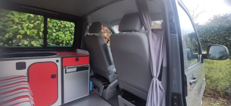 Intérieur de van aménagé avec cuisine et sièges.