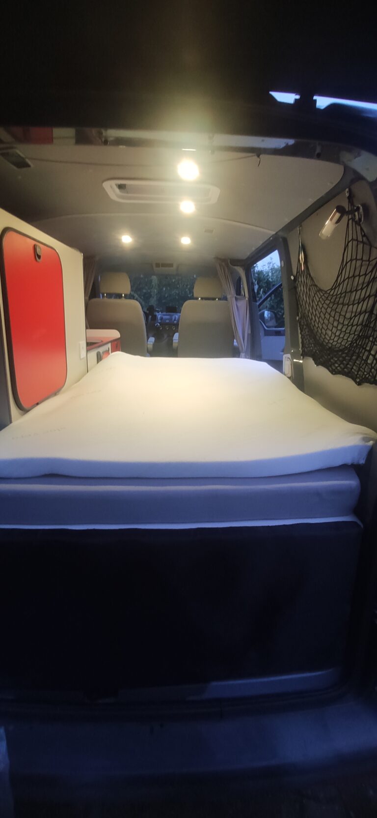 Lit aménagé dans un van confortable éclairé.