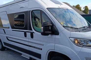 Camping-car blanc garé sur une allée pavée.