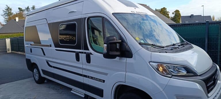 Camping-car blanc garé sur une allée pavée.