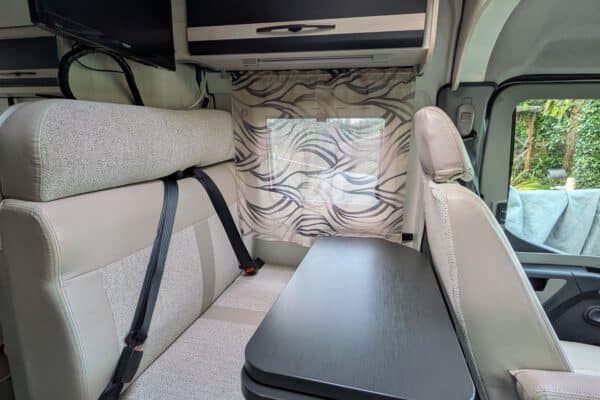 Innenansicht eines modernen Wohnmobil mit Tisch und Sitzen.