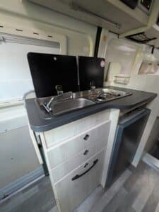 Cuisine de camping-car avec réfrigérateur et évier.