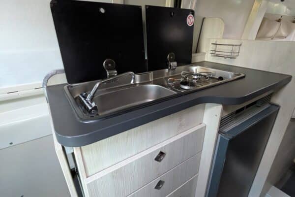 Küche von Wohnmobil mit Kühlschrank und Spüle.