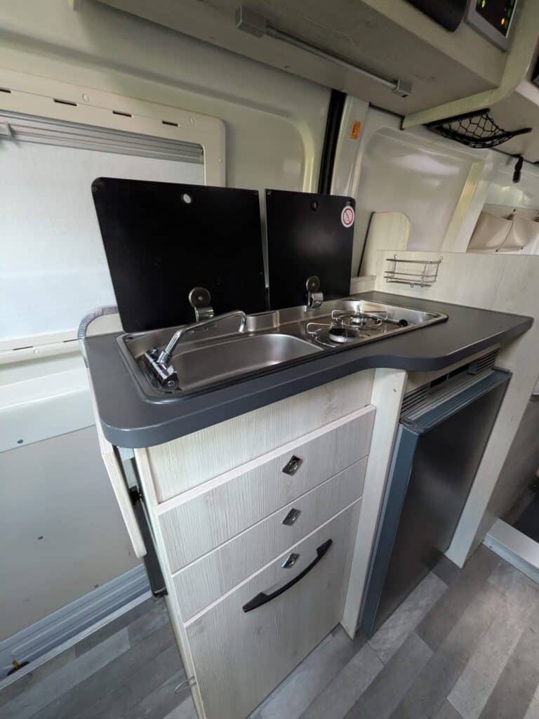 Cuisine de camping-car avec réfrigérateur et évier.