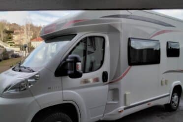 Camping-car blanc stationné près d'une maison