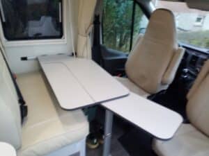 Intérieur d'un van avec sièges et table pliante.