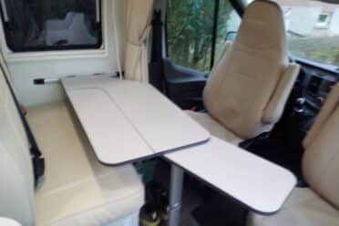 Intérieur d'un van avec sièges et table pliante.