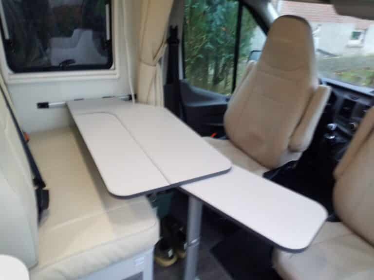 Intérieur d'un van avec sièges et table pliante.