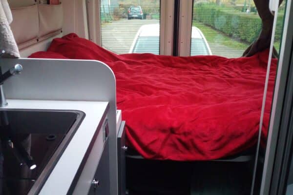Intérieur d'un camping-car avec lit et cuisine.