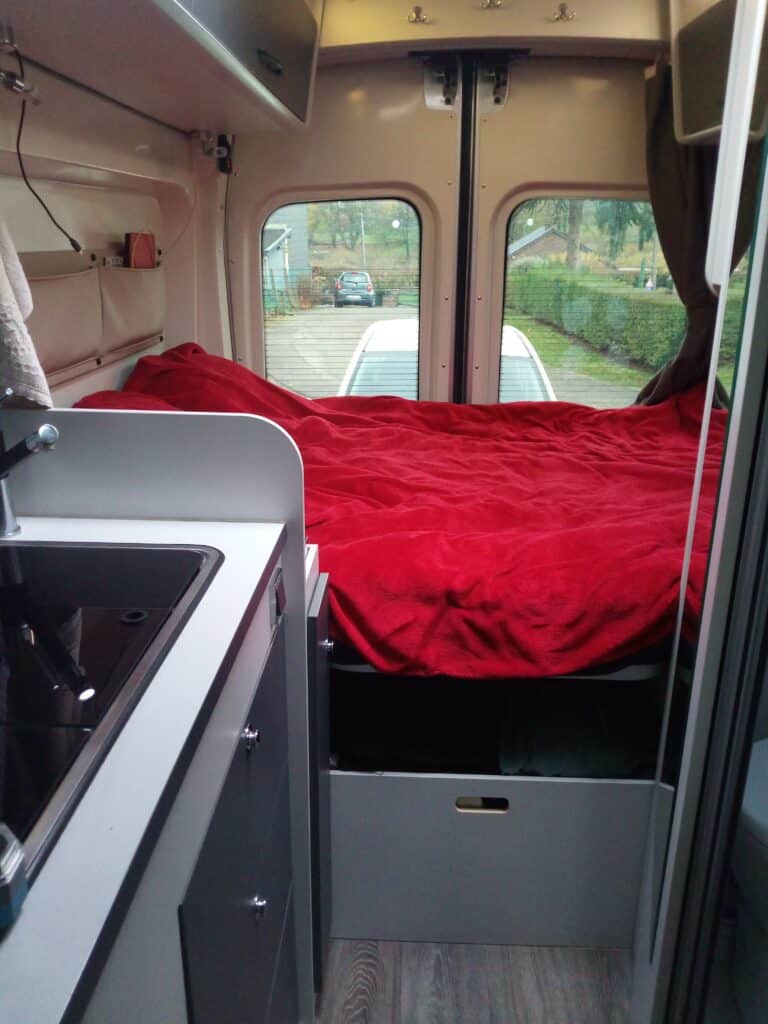 Intérieur d'un camping-car avec lit et cuisine.