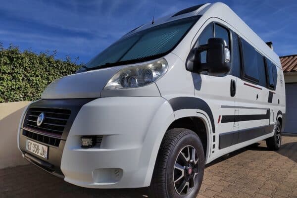 Weißer Wohnmobil geparkt auf gepflasterter Auffahrt.