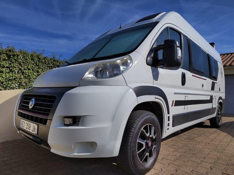 Camping-car blanc garé sur allée pavée.