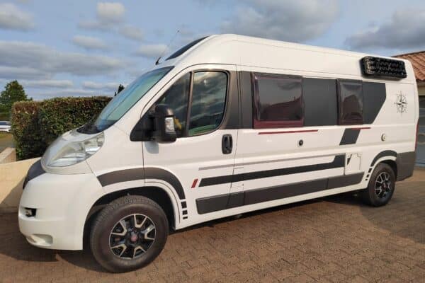 Wohnmobil weiß geparkt in der Einfahrt.