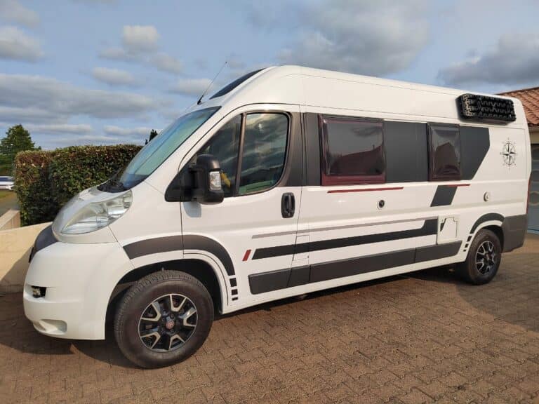 Camping-car blanc garé sur allée.
