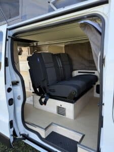 Intérieur d'un van aménagé avec banquettes noires.