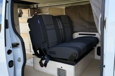 Intérieur d'un van aménagé avec banquettes noires.