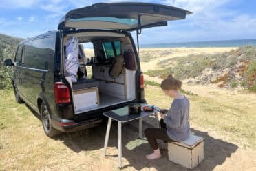 Camping-car aménagé sur plage ensoleillée.
