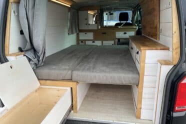Intérieur de van aménagé avec lit et rangement.