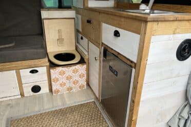 Intérieur d'un van aménagé avec cuisine et toilettes.